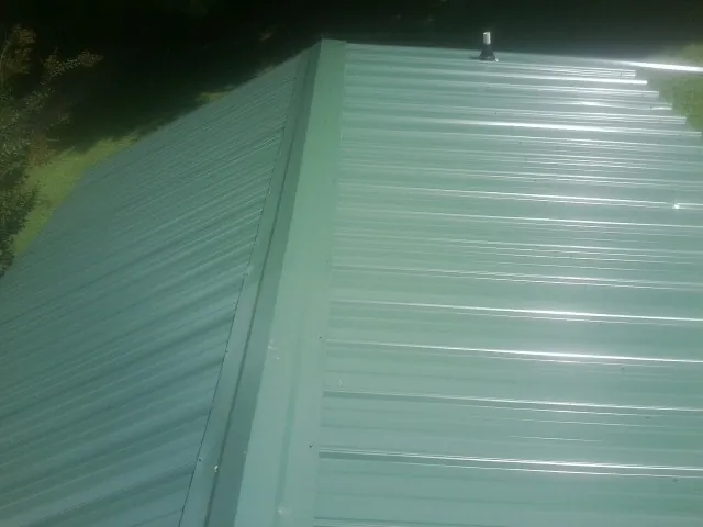 New green metal panels meeting at the ridge of a roof — Flat Roof Repair work by our crew in Humboldt