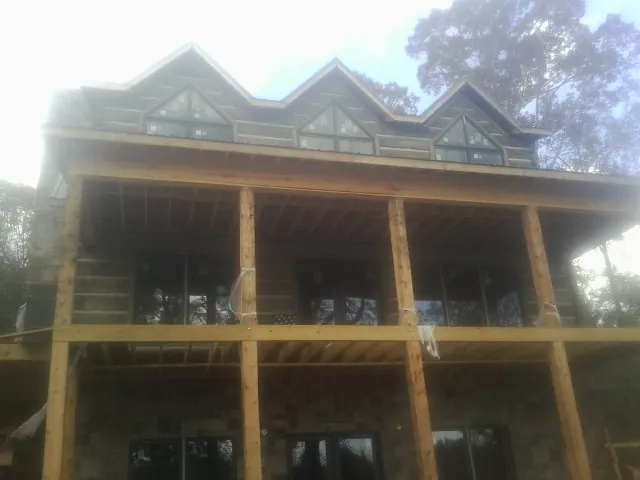 Dormers and porch framing on a large log home under construction — Roof Coating work by our crew in Humboldt